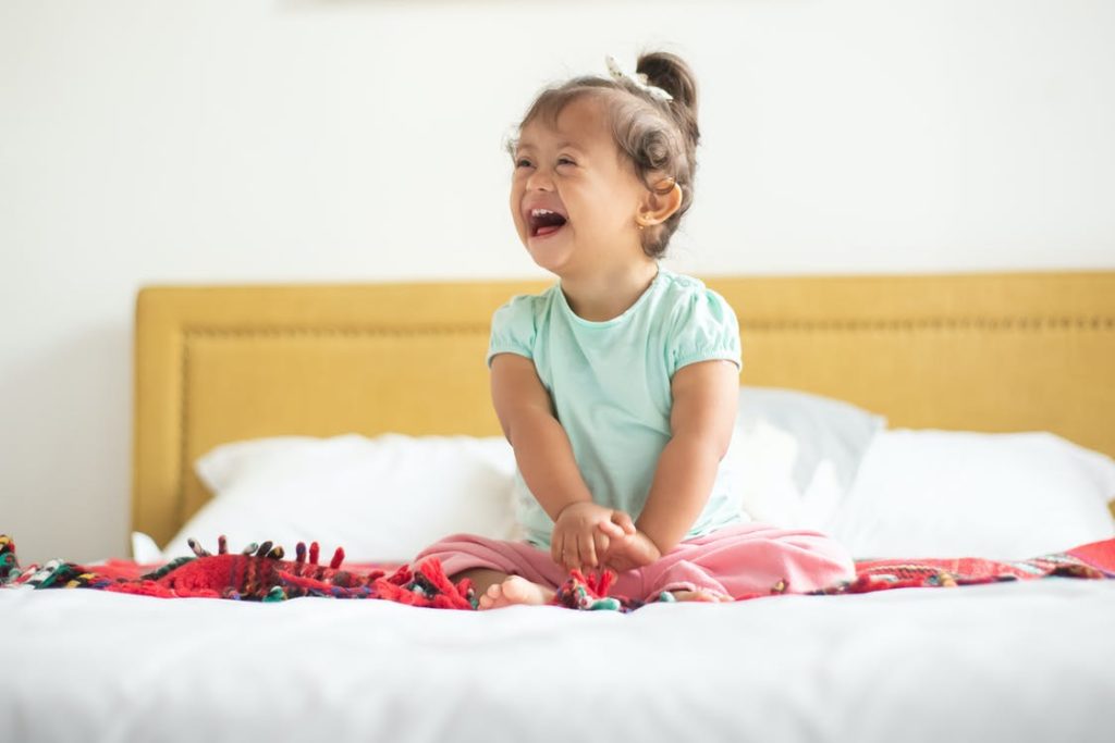A toddler smiling on a bed
