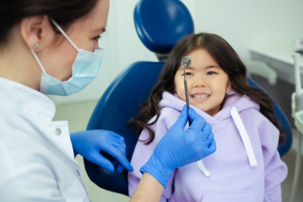 Dentist showing a dental tool to a happy child