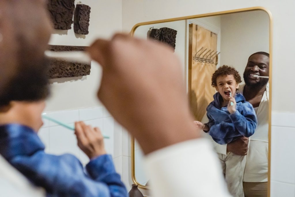 Father and son brushing their teeth in front of a mirror