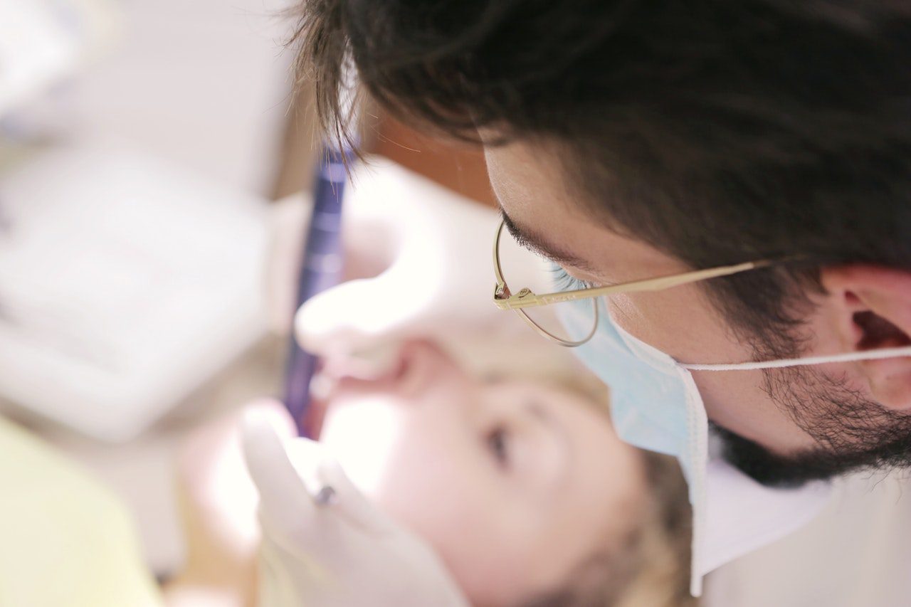 A DENTIST INSPECTING THE TEETH OF A SEDATED PATIENT